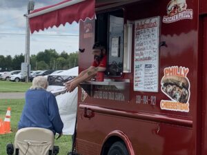 A worker for the Little Red Food Truck hands food to a customer.